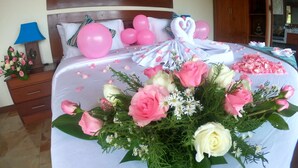 Un lit bien fait, décoré de ballons roses, un bouquet de fleurs et un tableau encadré accroché au mur.