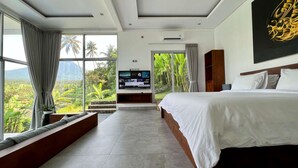 Une chambre d’hôtel moderne dotée d’un grand lit, d’une télévision et offrant une vue sur une végétation luxuriante.