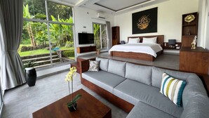 Une chambre moderne avec un grand lit, un canapé, une télévision et une vue sur un jardin.
