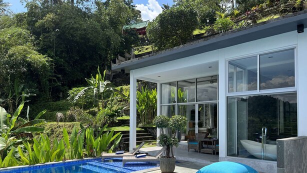 Une maison moderne dotée d’une piscine, de grandes baies vitrées et d’un jardin luxuriant.