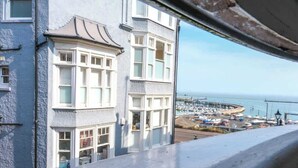 A coastal view from a window overlooking a marina with boats, a pier, and a building with bay windows. - Elizabeth | Seaside charm | Iconic location (Ramsgate)