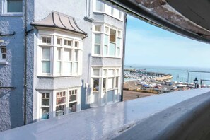 A coastal view from a window overlooking a marina with boats, a pier, and a building with bay windows.