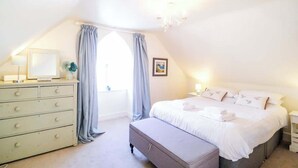 A bedroom with a bed, a dresser, a nightstand, a window with curtains, and a chandelier. - Elizabeth | Seaside charm | Iconic location (Ramsgate)
