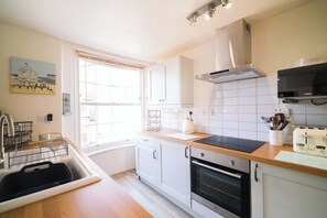 A kitchen with white cabinets, a black stove, and a window.