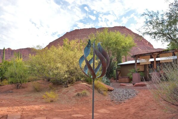 A rustic building with a mountain in the background, surrounded by desert vegetation.