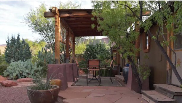 A covered patio area with a wooden pergola, a table and chairs, and a potted plant. - Desert Oasis & Spa - 30 Night Rental - Kayenta, Tuacahn & Zion  (Ivins)