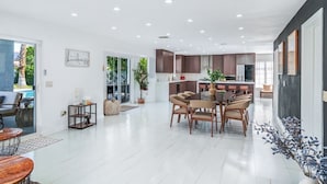 Una cocina moderna con armarios oscuros, un comedor con una mesa redonda y sillas, y un ventanal que proporciona luz natural.