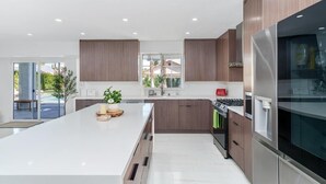 Una cocina moderna con una isla grande, electrodomésticos de acero inoxidable y armarios de madera.