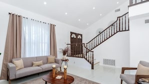 Un salón amplio con sofá, una mesa de centro y una escalera.