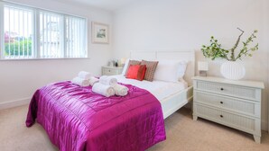 A bedroom with a bed, a nightstand, a dresser, and a window with blinds. - Indigo (St Ives)