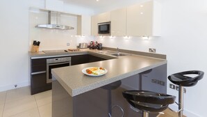 A modern kitchen with a granite countertop, stainless steel appliances, and a built-in microwave. - Indigo (St Ives)
