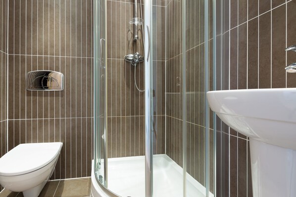 Une salle de bain moderne avec une douche à parois de verre, des toilettes blanches et un lavabo blanc.