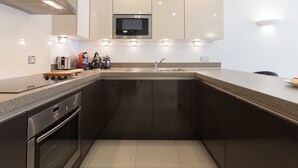 A modern kitchen with stainless steel appliances, a built-in microwave, and a granite countertop. - Indigo (St Ives)