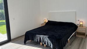 Un dormitorio con una cama, dos mesitas de noche con lámparas, una ventana y vistas al verdor exterior.