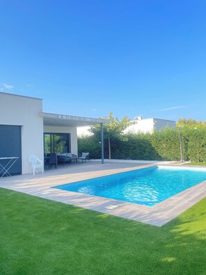 A modern house with a swimming pool, a patio with outdoor furniture, and a well-maintained lawn. - Stunning Modern Villa with Pool – Just a 5-minute walk from the beach! (El Mas Pinell)