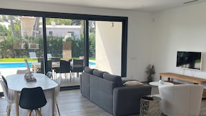 Una sala de estar moderna con un sofá gris, una mesa redonda blanca y un televisor en la pared.