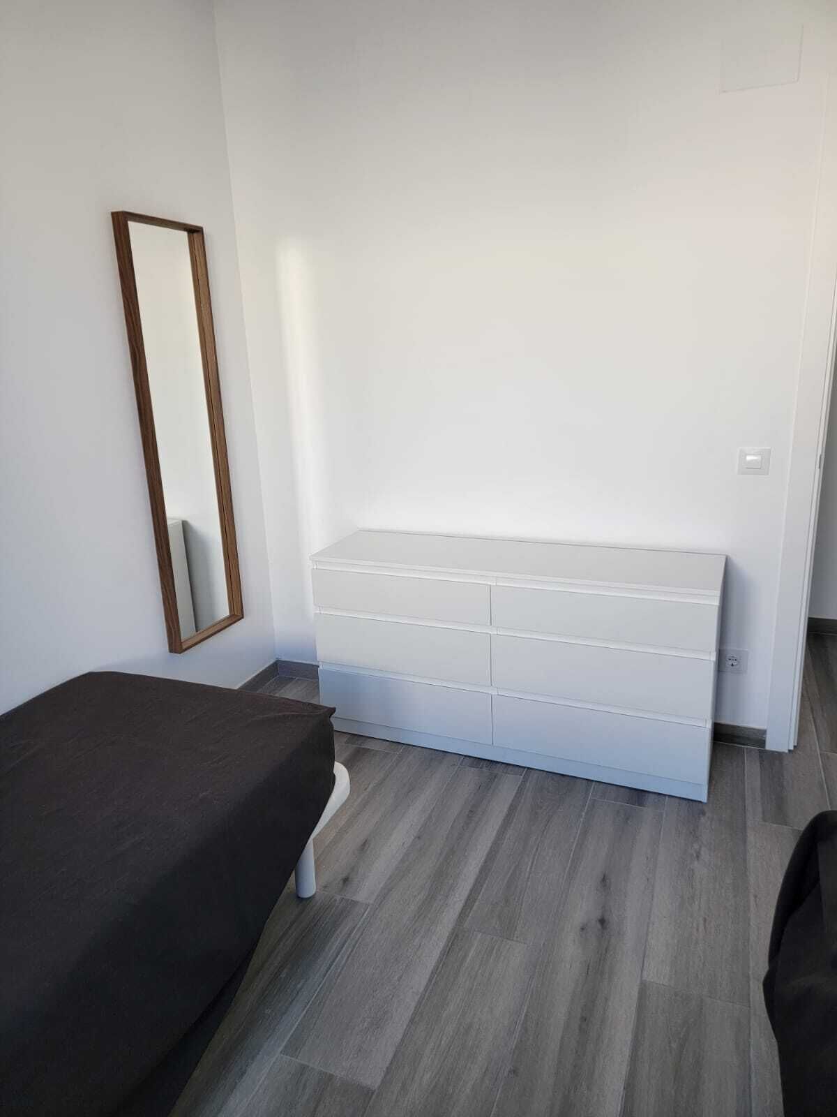 A bedroom with a bed, a dresser, and a mirror.