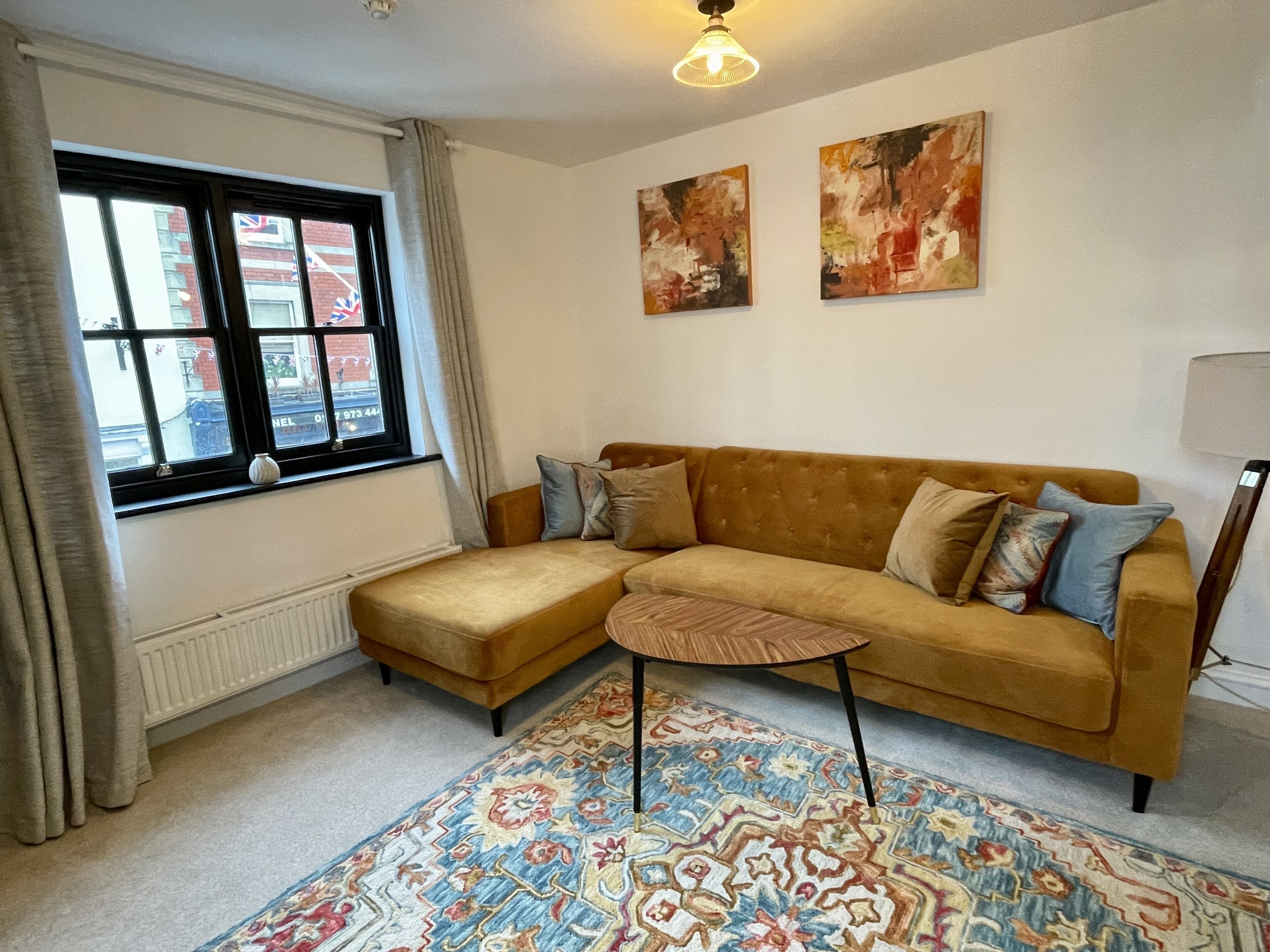 A living room with a sofa, a patterned rug, and two abstract paintings on the wall.
