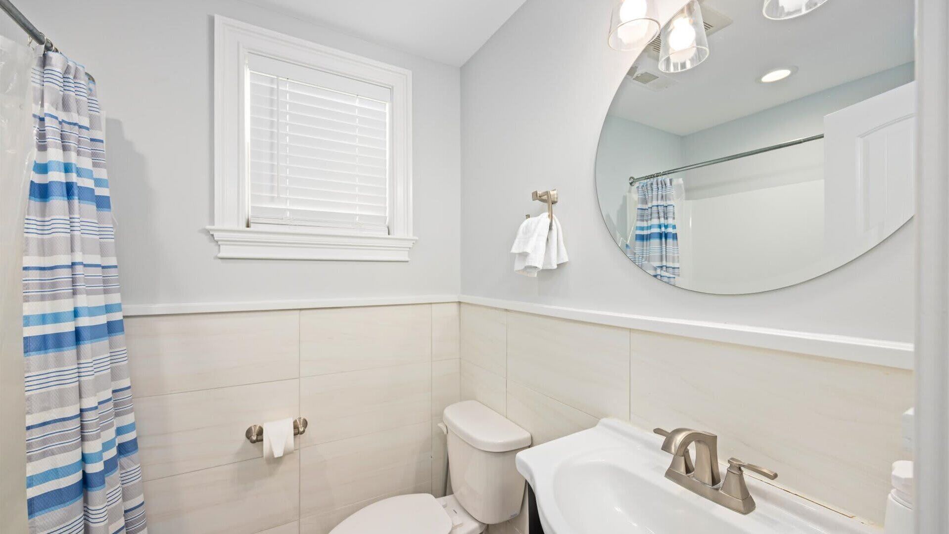 A bathroom with a toilet, sink, and a window with blinds.