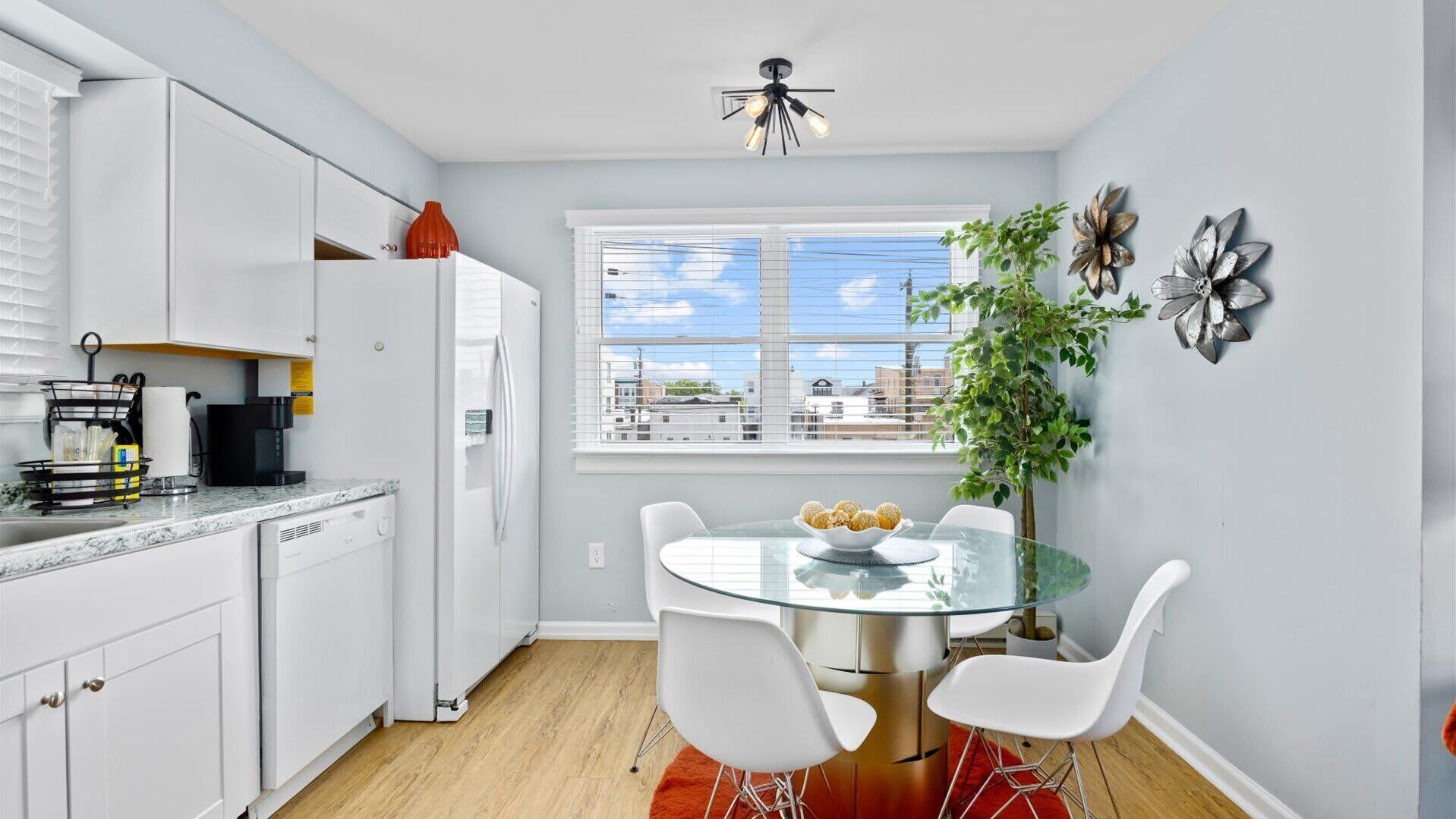 A modern kitchen with white cabinets, a coffee machine, and a window with a city view.