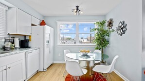 A modern kitchen with white cabinets, a coffee machine, and a window with a city view. - 2BR Beach Escape - Walk to Boardwalk & Downtown OC (Ocean City)