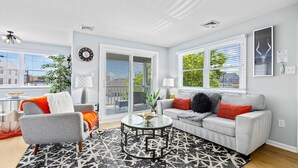 A modern living room with a grey sofa, a round coffee table, and a patterned rug. - 2BR Beach Escape - Walk to Boardwalk & Downtown OC (Ocean City)