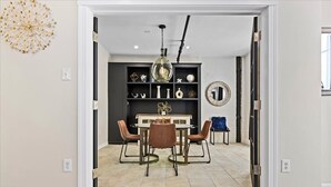 A dining area with a round table, four chairs, and a decorative light fixture. - Vibrant AC Loft w/ Beach Views, Sauna, Jacuzzi Tub (Atlantic City)