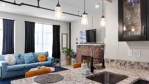 A modern living room with a blue sofa, a coffee table, and a fireplace. - Vibrant AC Loft w/ Beach Views, Sauna, Jacuzzi Tub (Atlantic City)