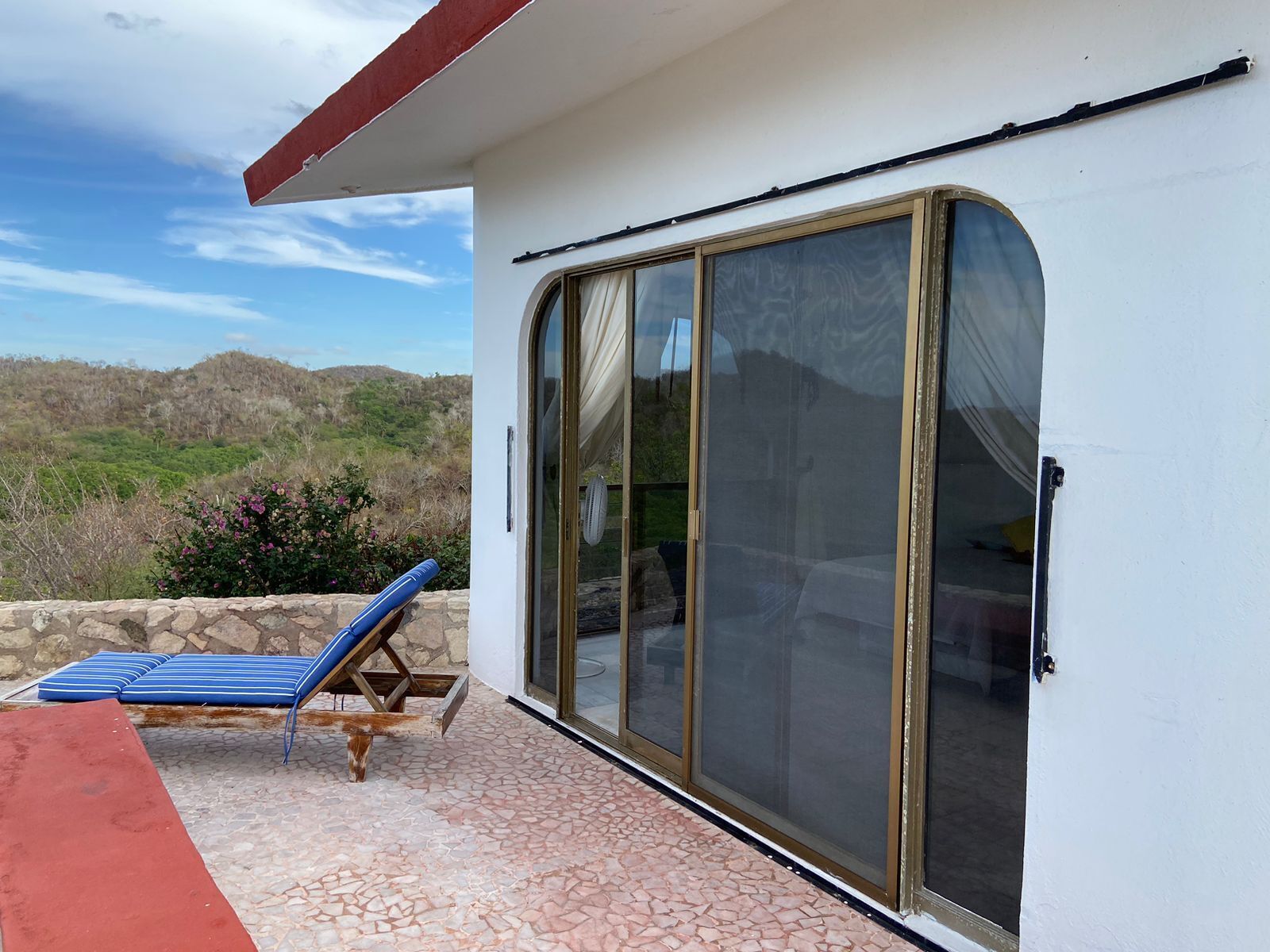 A room with a large sliding glass door, a red carpet, and a blue lounge chair.