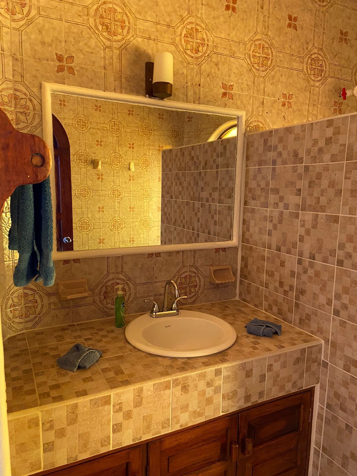 A bathroom with a round sink, a mirror, a towel rack, and a soap dish.