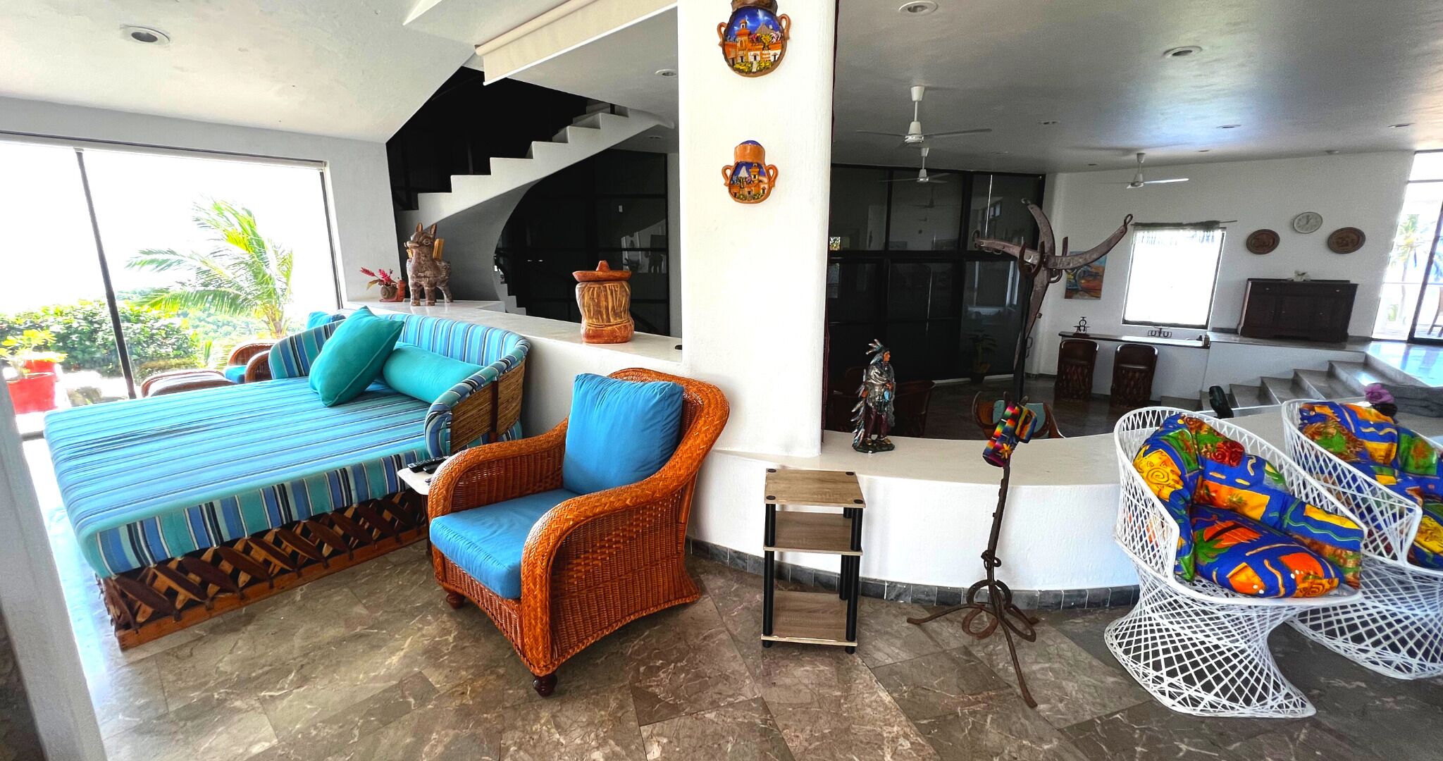 Amplia sala de estar con sofá, sillones y comedor con una silla blanca.