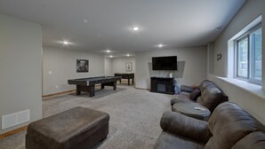 A spacious living room with a pool table, a sofa, and a television.