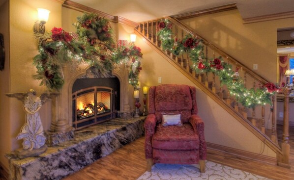 A grand staircase with a Christmas garland, a fireplace with a mantelpiece, and a plush armchair. - Birdcage- within minutes of downtown Deadwood (Deadwood)
