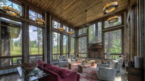 A spacious living room with large windows, a fireplace, and modern furniture. - Majestic Cabin near Mount Rushmore (Keystone)