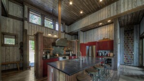 A spacious kitchen with a large island, wooden walls, and a high ceiling. - Majestic Cabin near Mount Rushmore (Keystone)