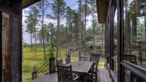 A wooden deck with a table and chairs, overlooking a forested area. - Majestic Cabin near Mount Rushmore (Keystone)