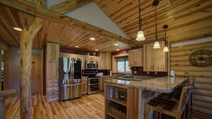 Una cocina rústica con armarios de madera, electrodomésticos de acero inoxidable y una isla central con asientos tipo barra.