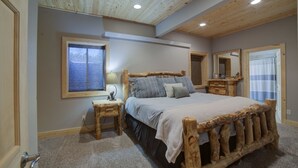 Un dormitorio con estructura de cama de madera, una mesita de noche, una ventana con vistas y un espejo.