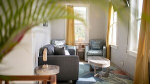 A cozy living room with a grey sofa, a patterned armchair, and a small wooden table. - Sugarview Villa Cottage:  Coral Bay, Ocean View (St John)