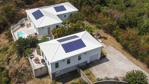 Two houses with solar panels, a swimming pool, and a well-maintained garden.