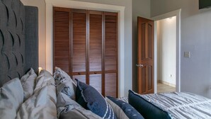 A bedroom with a bed, pillows, a wardrobe, and a door leading to another room. - Sugarview Villa Cottage:  Coral Bay, Ocean View (St John)