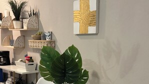 Un espace repas moderne avec une table en verre entourée de chaises blanches, une plante en pot et un élément décoratif mural.