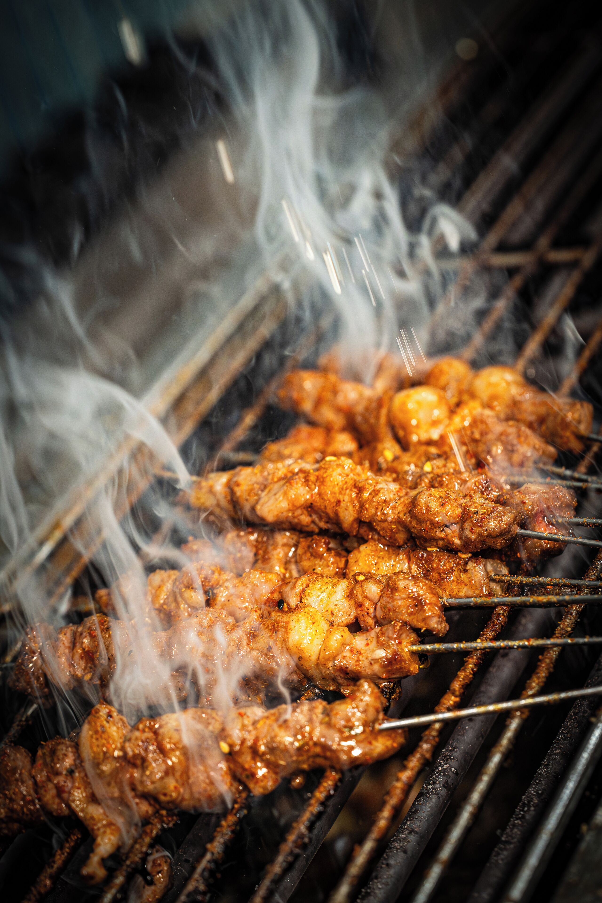Skewers of meat being grilled on a barbecue.