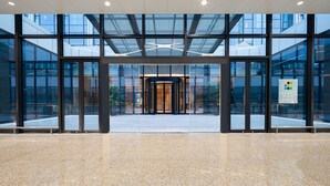 Una entrada de hotel moderna con fachada de vidrio, una puerta giratoria central y un letrero que indica el nombre 'Hyatt Place'.
