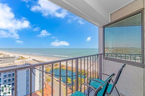 A balcony with a view of the beach and ocean.