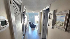 Un couloir avec un ventilateur de plafond, une horloge et une chaise au fond.