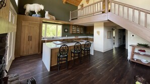 Een ruime keuken met een centraal eiland, houten kasten en een stenen openhaard.