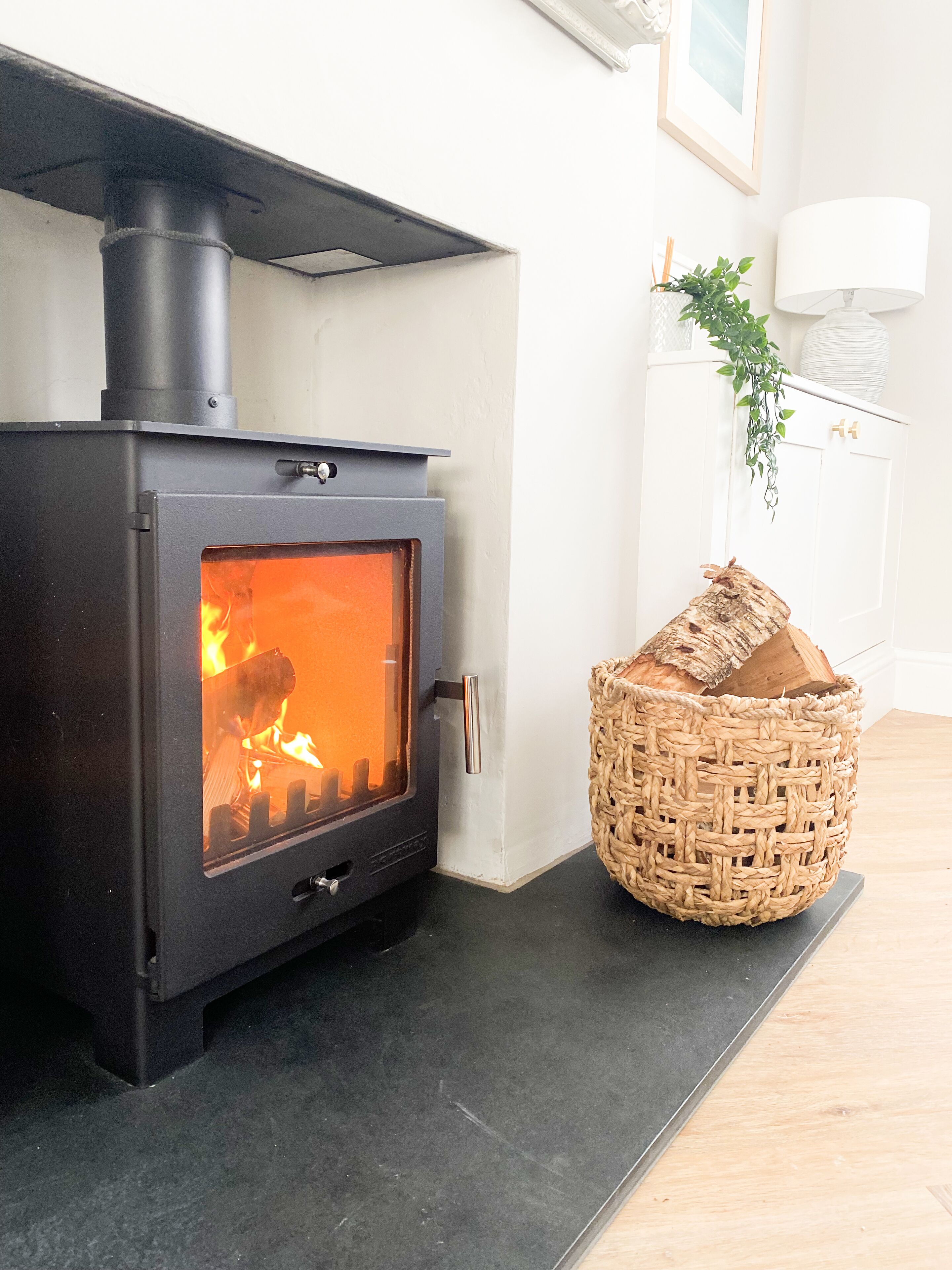 A modern wood-burning stove with a glass door, a metal handle, and a chimney.