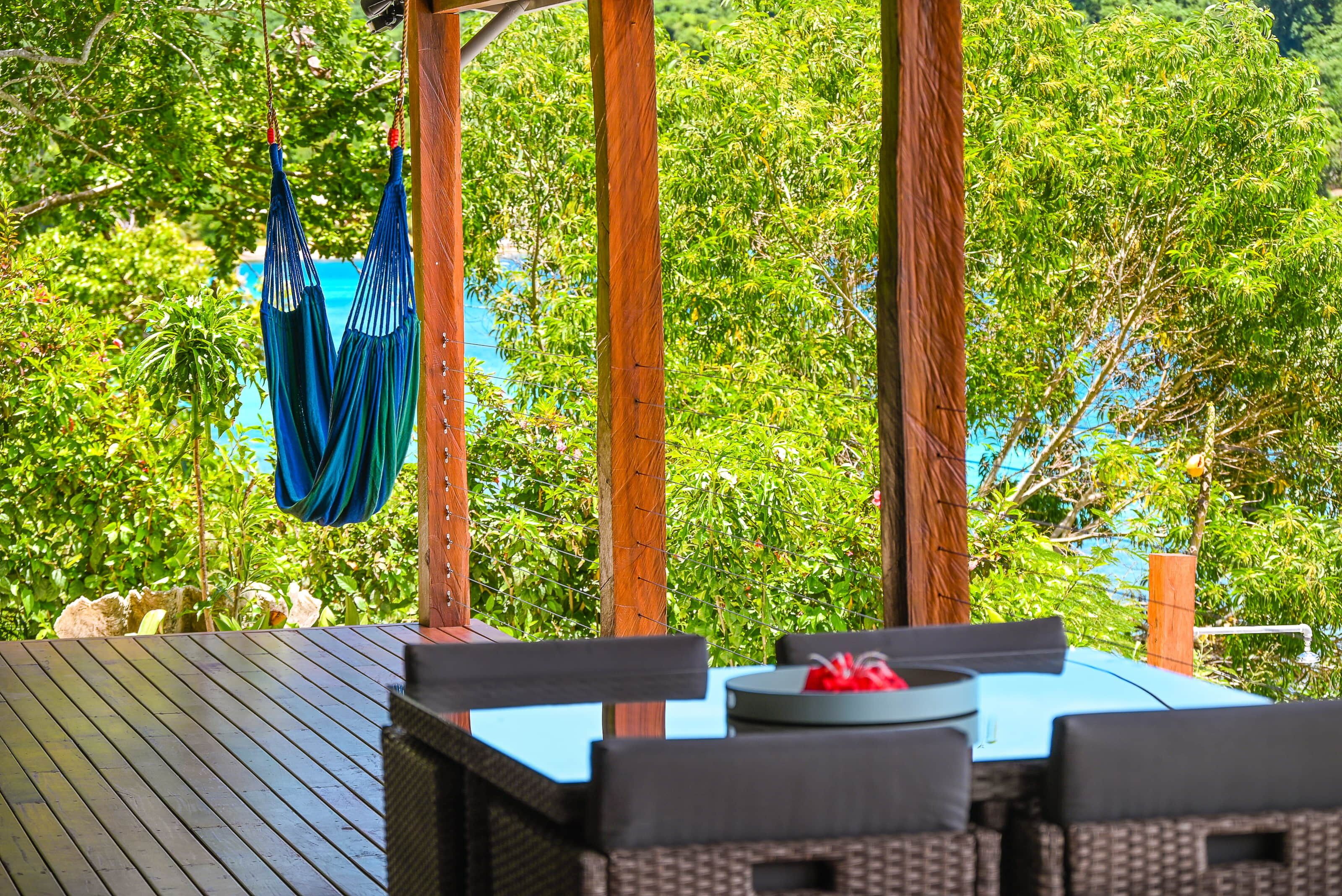 Un espace extérieur aménagé avec une terrasse en bois, une table et des chaises, et un hamac.