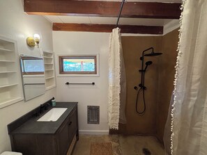 Ein Badezimmer mit einer Badewanne, einem Fenster, einem Handtuchhalter und einem Waschbecken.